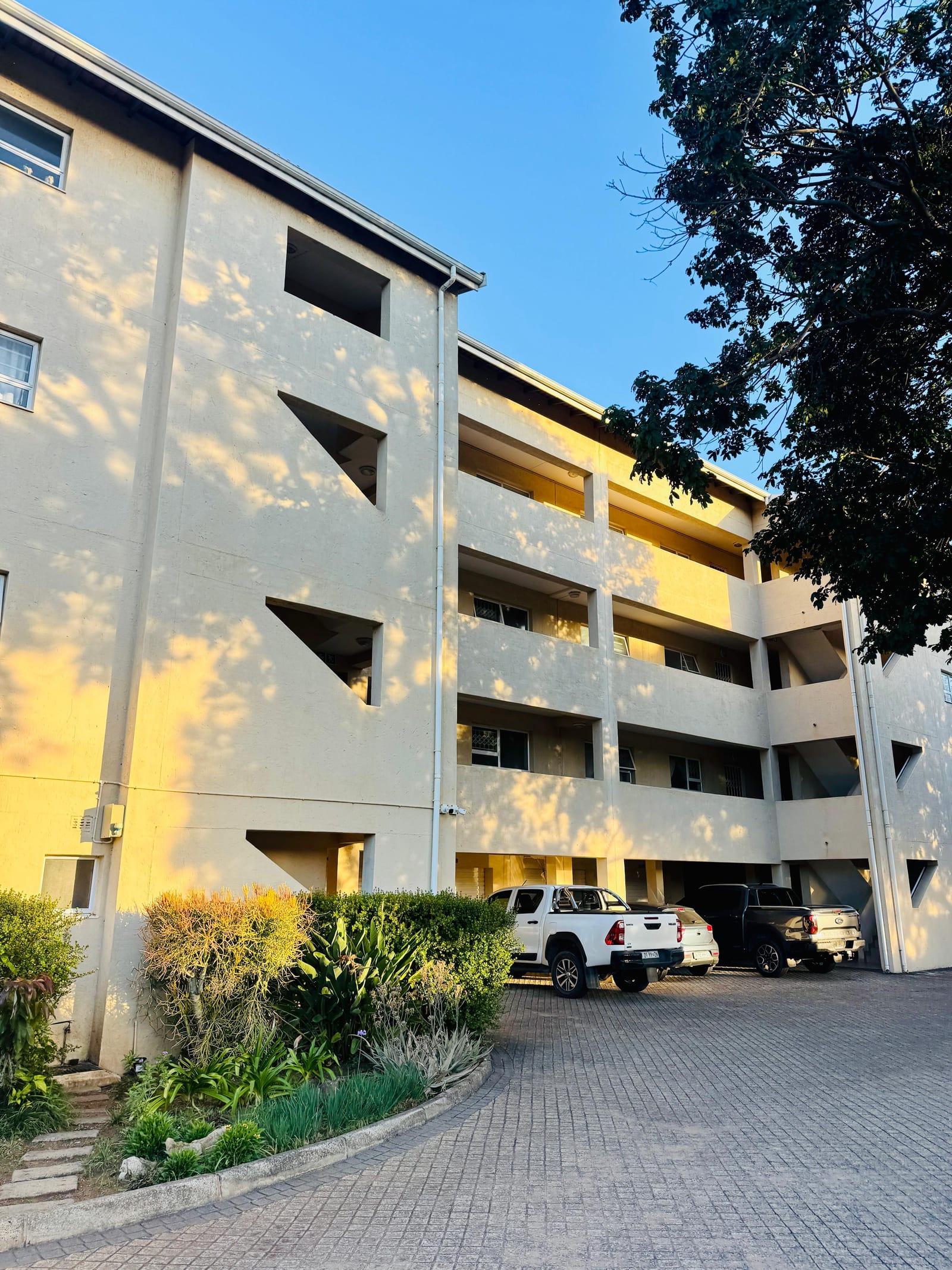 The block from the driveway, with covered parking beneath in late afternoon light