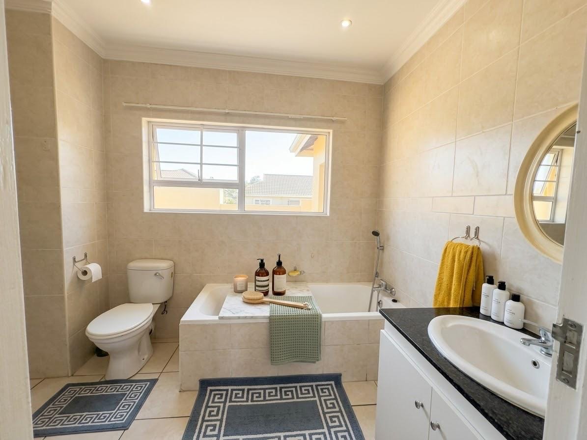 Bathroom with a full bath, toilet, vanity basin and a round mirror