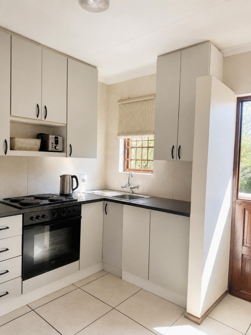 Fitted kitchen with oven, hob, granite counter and a window over the sink