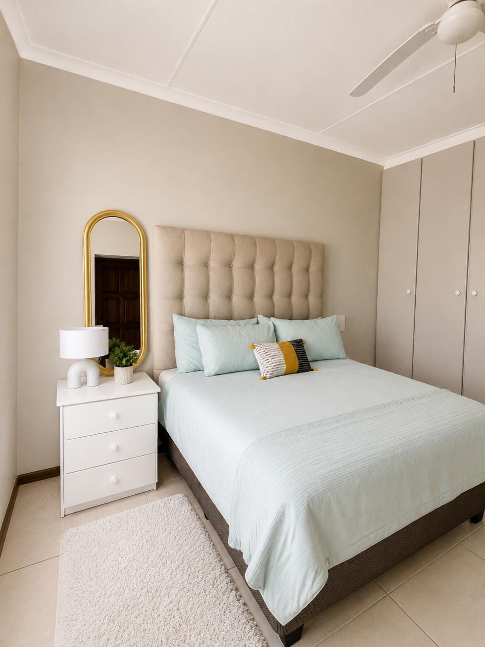 Main bedroom with an upholstered headboard and arched mirror