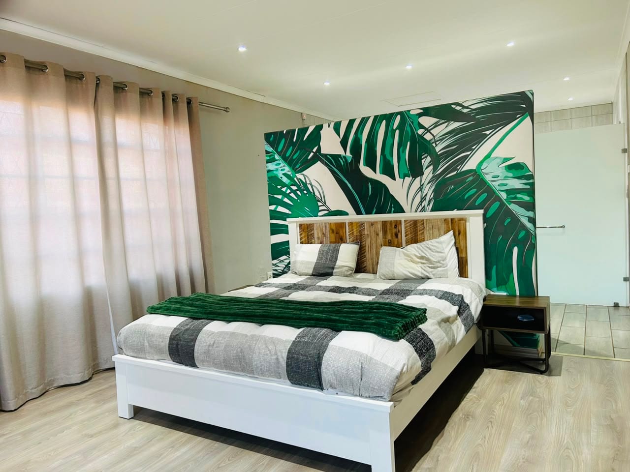 Main bedroom with a timber headboard and an en-suite beyond